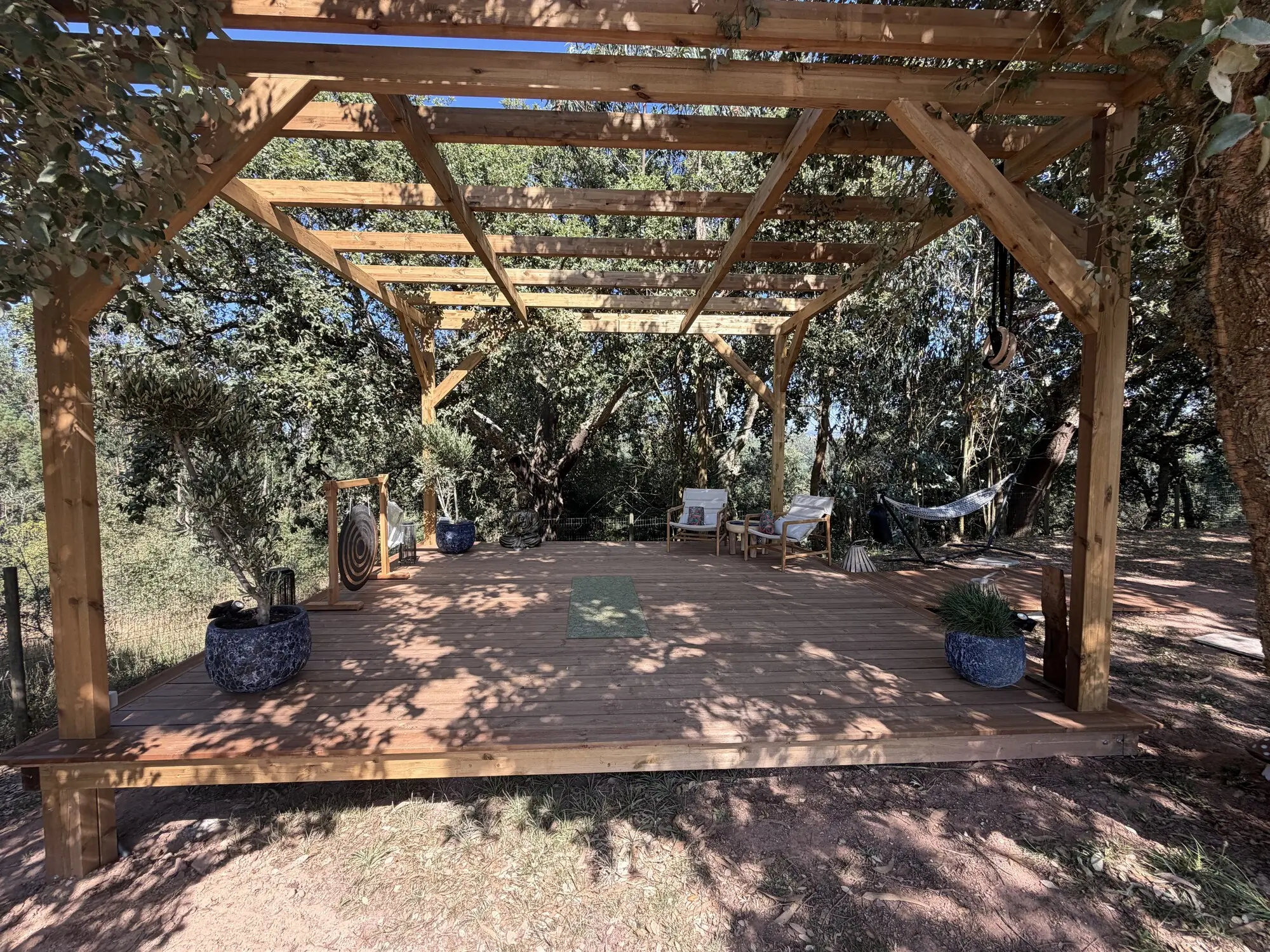 Completed outdoor therapeutic space at the Pathfinder Project, with a timber platform, pergola, seating, gong and surrounding woodland